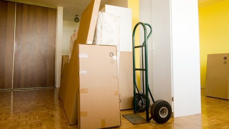 Carretilla de mudanzas junto a armarios y muebles embalados en un pasillo