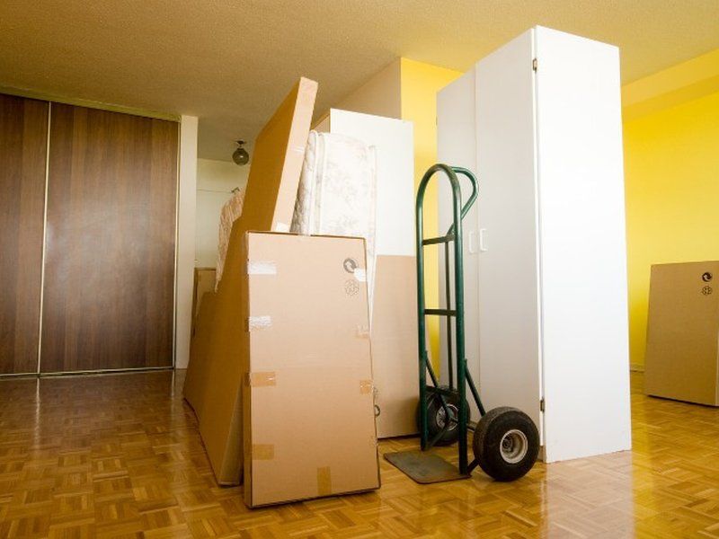 Carretilla de mudanzas junto a armarios y muebles embalados en un pasillo
