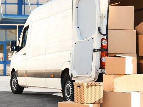 Furgoneta de mudanzas con las puertas abiertas y cajas apiladas junto a ella