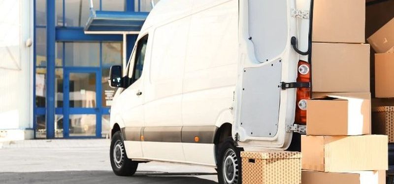 Furgoneta de mudanzas con las puertas abiertas y cajas apiladas junto a ella