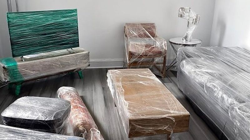 Sofá, televisor, mesa y alfombras protegidos con film para la mudanza