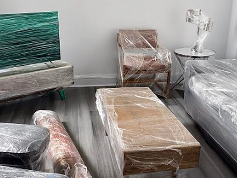 Sofá, televisor, mesa y alfombras protegidos con film para la mudanza