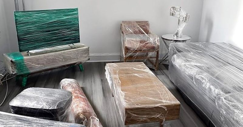 Sofá, televisor, mesa y alfombras protegidos con film para la mudanza