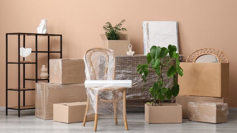 Silla, cuadros y cajas embalados en un salón, preparados para la mudanza