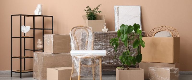 Silla, cuadros y cajas embalados en un salón, preparados para la mudanza