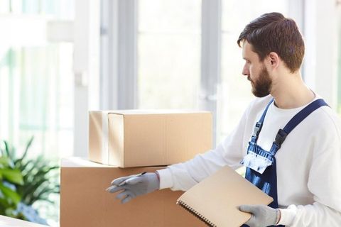 Operario de mudanzas con guantes revisando el inventario de las cajas