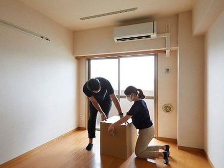 Dos personas cerrando una caja de mudanza en un piso vacío
