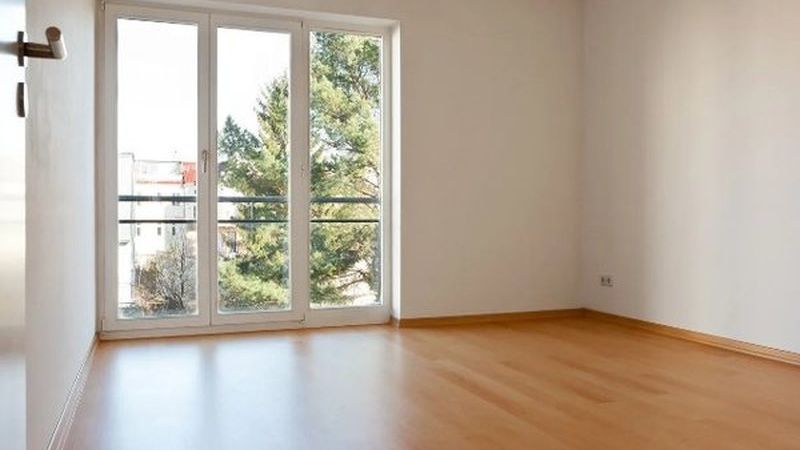Salón vacío con suelo de parquet y ventanal, listo para entrar a vivir