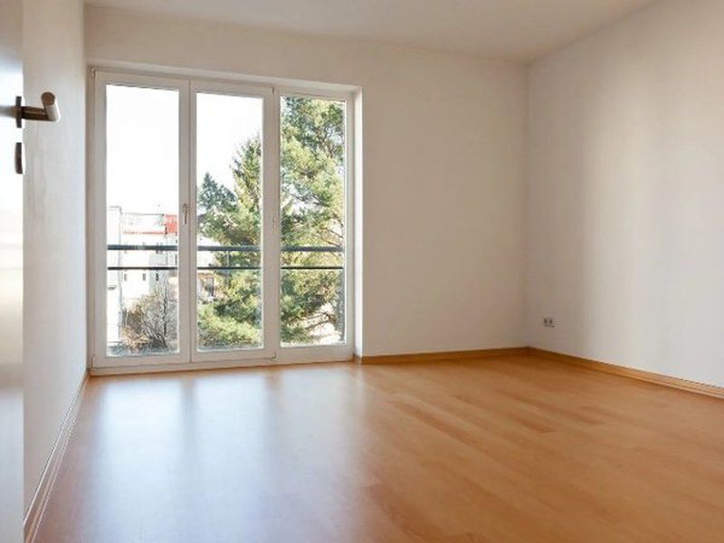 Salón vacío con suelo de parquet y ventanal, listo para entrar a vivir