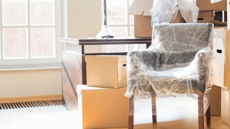Sillón envuelto en film entre cajas de mudanza junto a una ventana